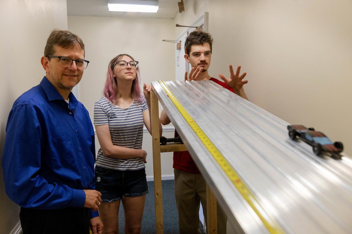 Gregory Wietrzykowski '26, Alaina Snider '27, and professor Peter Sheldon roll a toy car down a ramp as part of their summer research 
