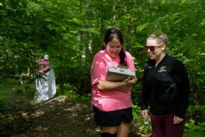 Biology professor Erin Heller and Gracie Oliver talk in a wooded area while collecting ticks for their project. 